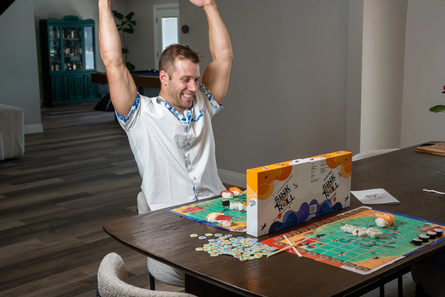 A player celebrating at the table during a game of Sink That Roll with sushi